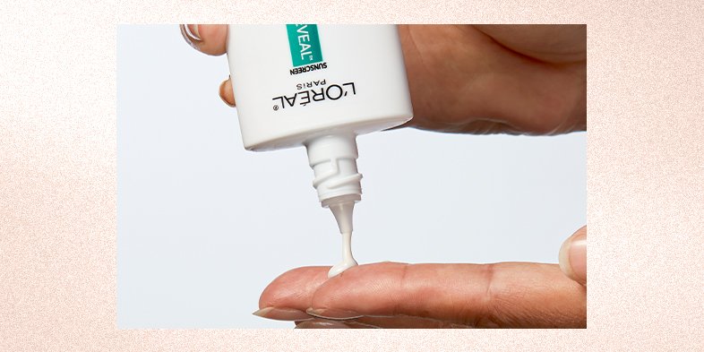 A woman pouring a face serum into hands